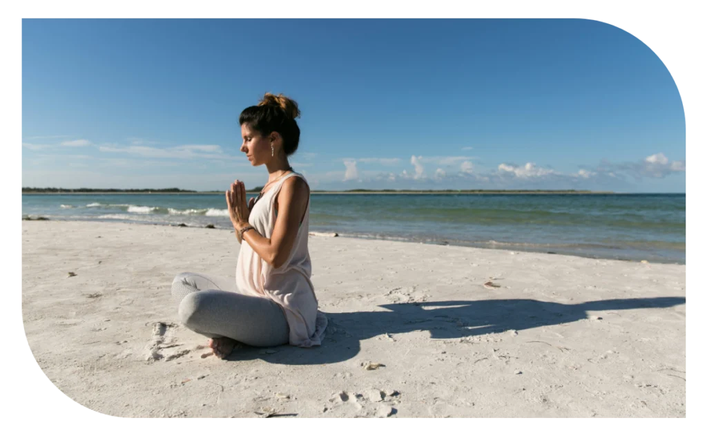 A woman sitting on the beach in front of the ocean.