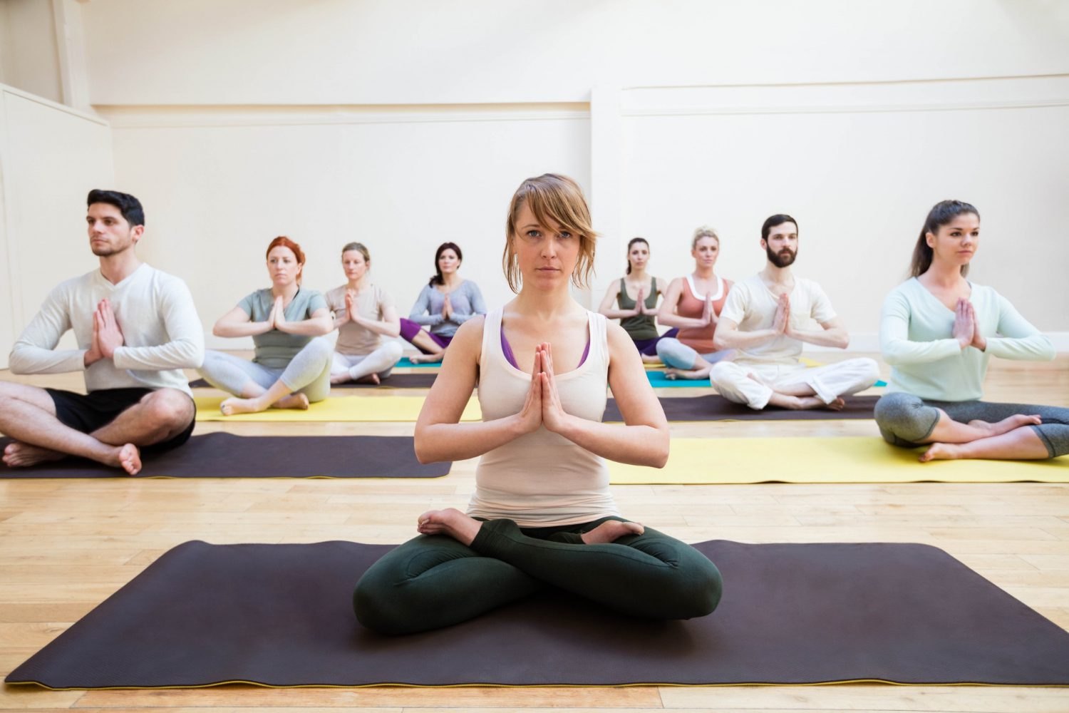 A group of people sitting in the middle of a yoga class.