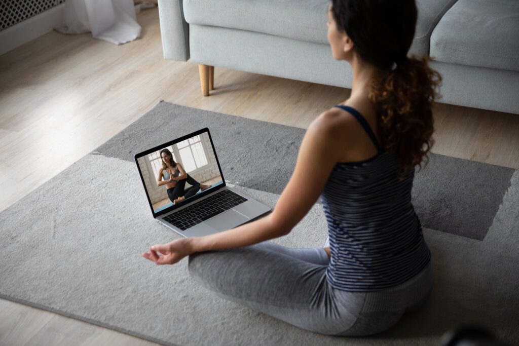 A woman sitting on the ground in front of a laptop.