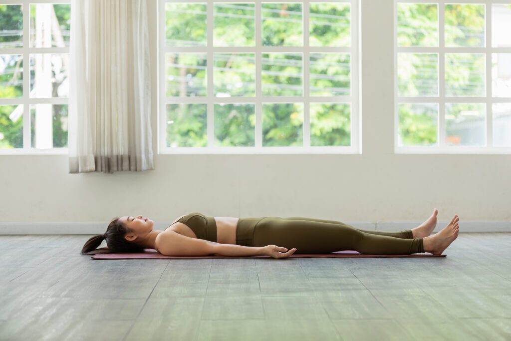 A woman is laying on the floor in a yoga pose.