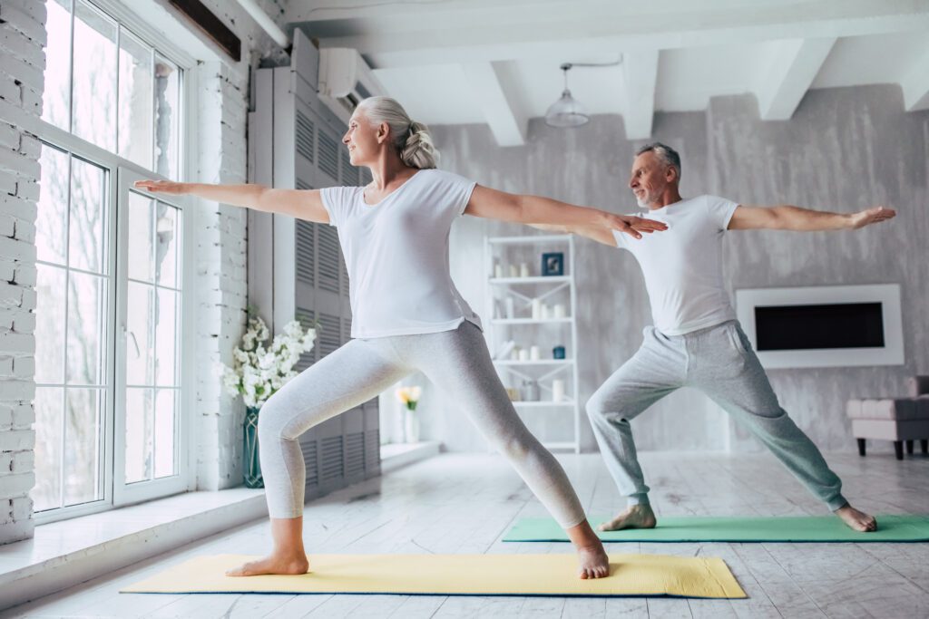 Senior couple at home Two people doing yoga in a living room.